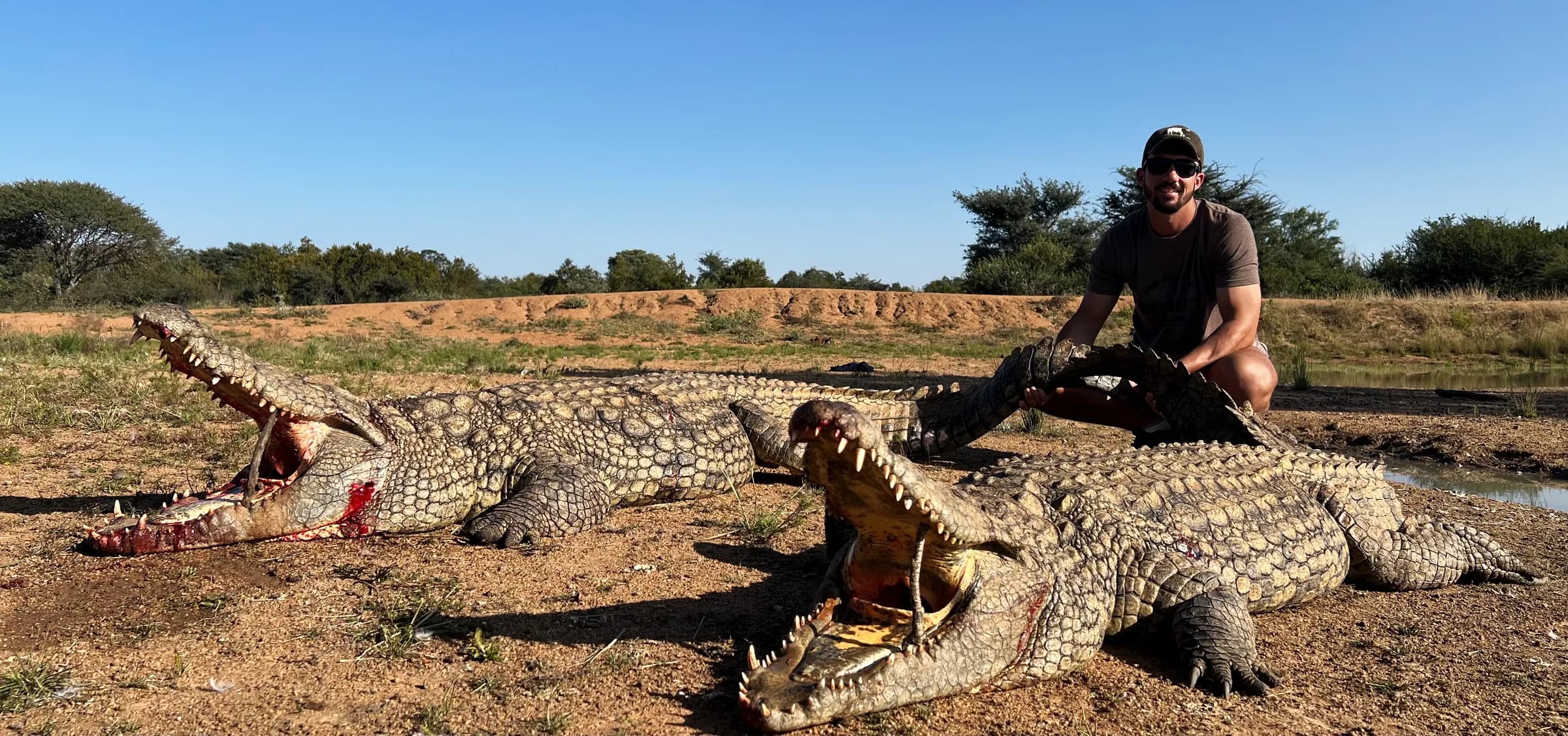 A hunter with a Nile crocodile on the riverbank