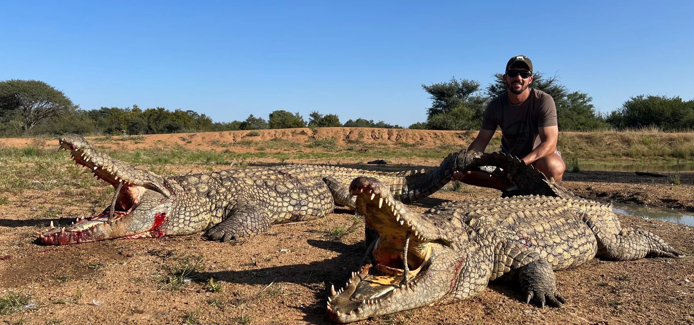A hunter with a Nile crocodile on the riverbank