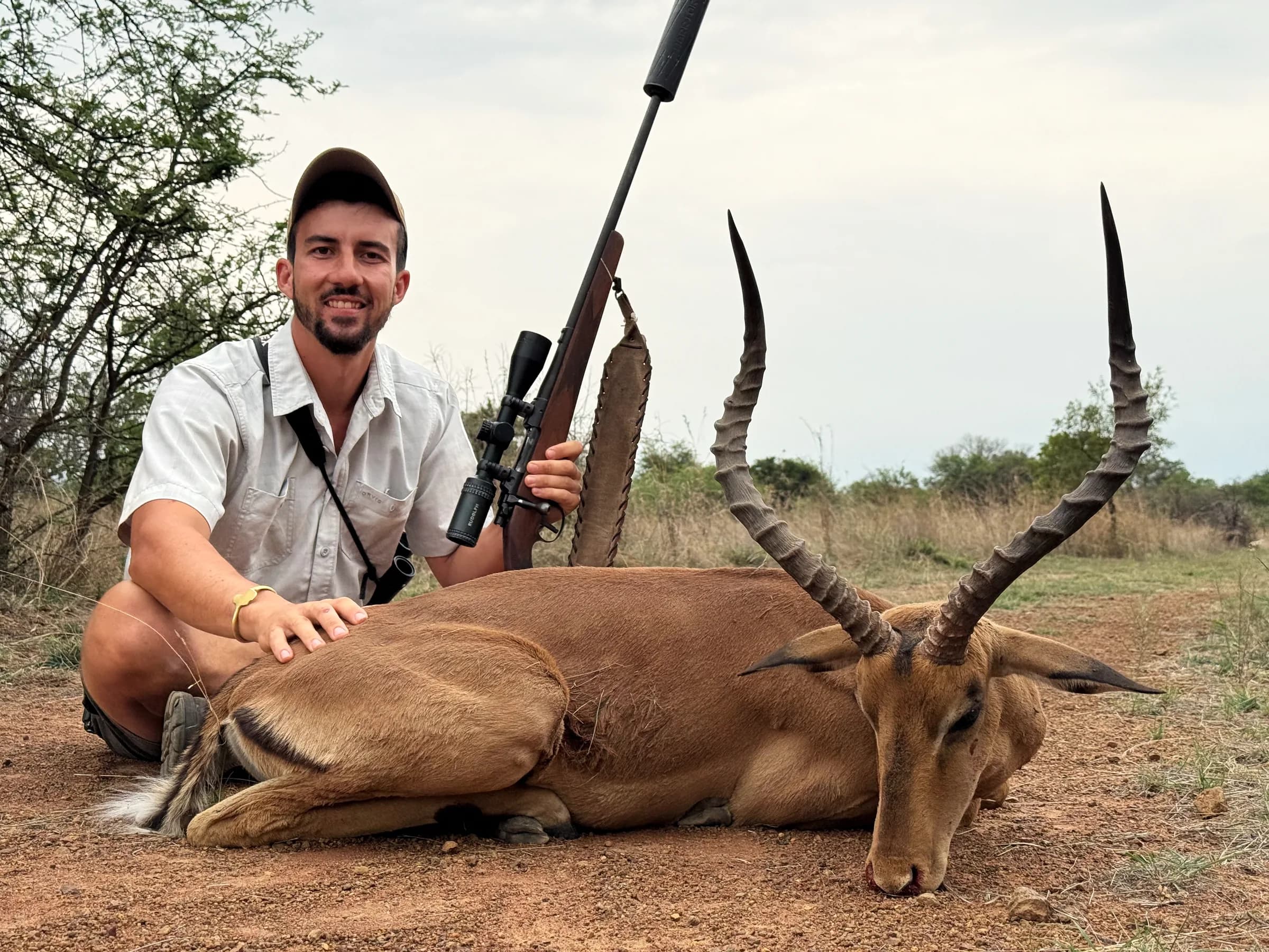 A hunter with an impala ram and his rifle
