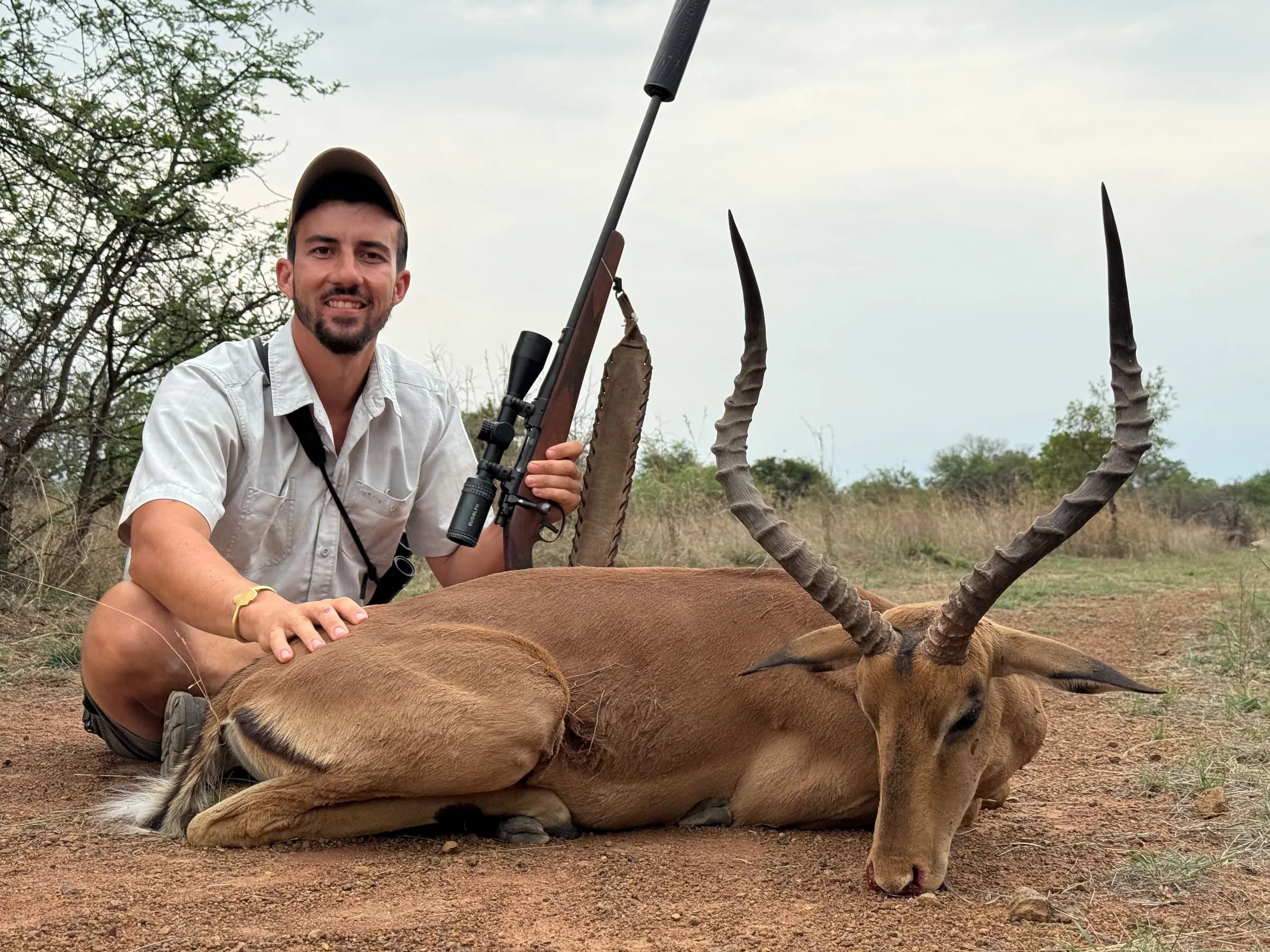 A hunter with an impala ram and his rifle