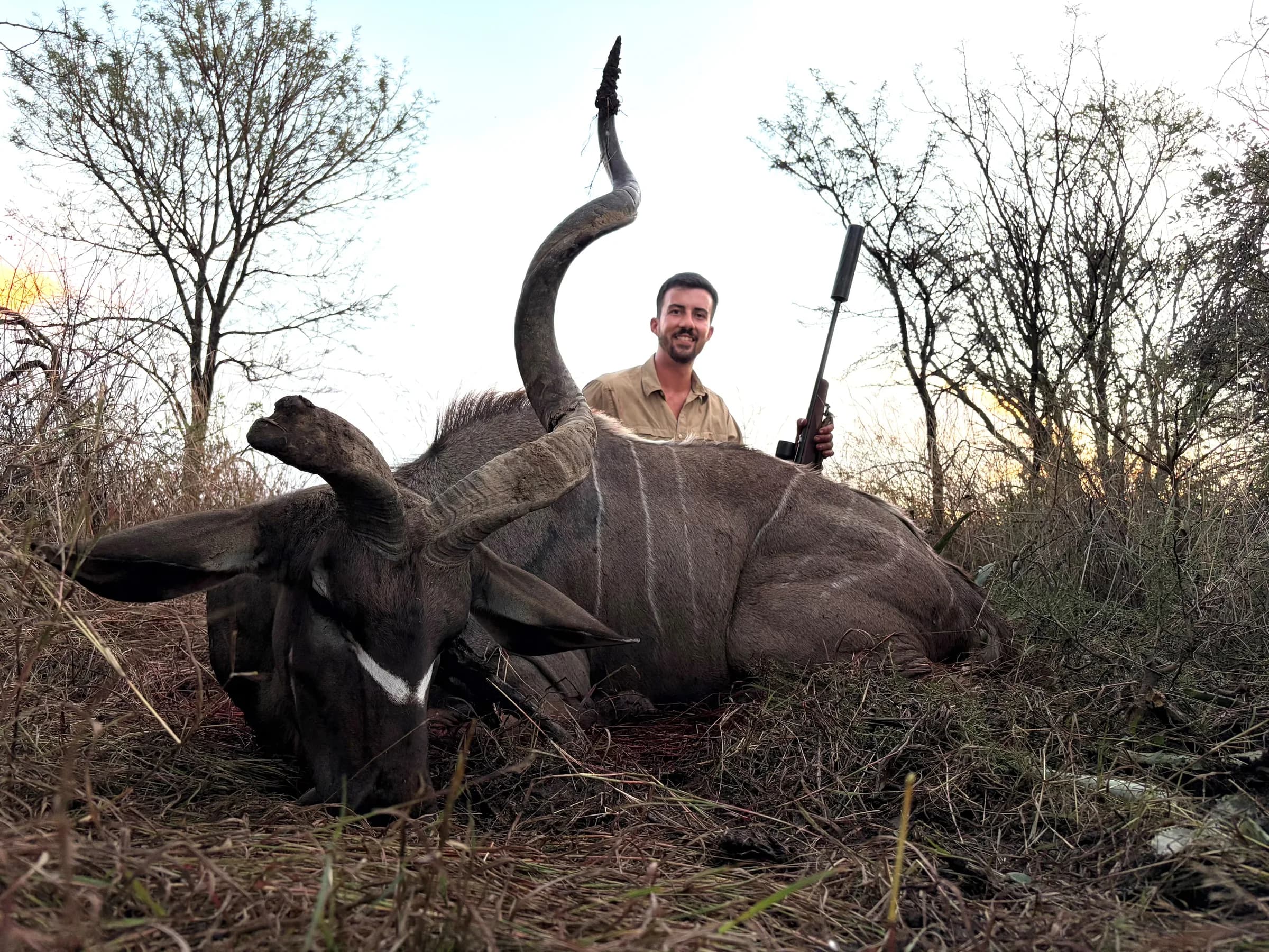 A hunter with a kudu bull in the late afternoon