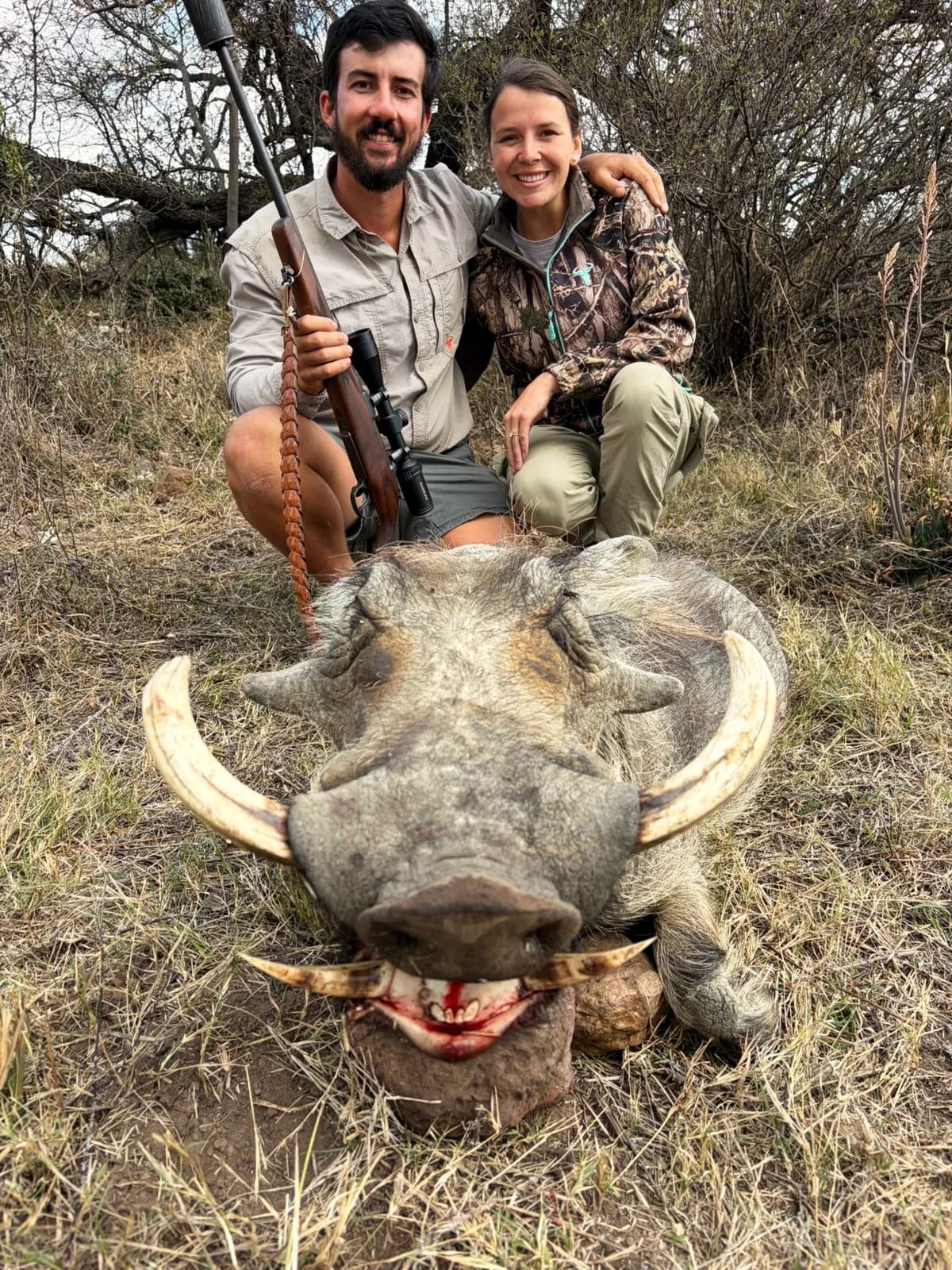 Two hunters with a heavy-tusked warthog boar